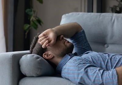 En deprimerad man ligger p&aring; en soffa 
