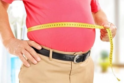 Homem com uma fita m&eacute;trica na barriga 