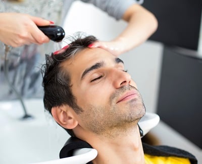 Ein Mann, der eine Haarpflege zur Vorbeugung von Geheimratsecken erh&auml;lt