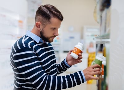 Ein Mann w&auml;hlt in einer Apotheke Potenzpillen aus